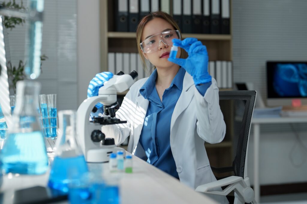Scientist wearing safety gear examines a sample in a high-tech laboratory.